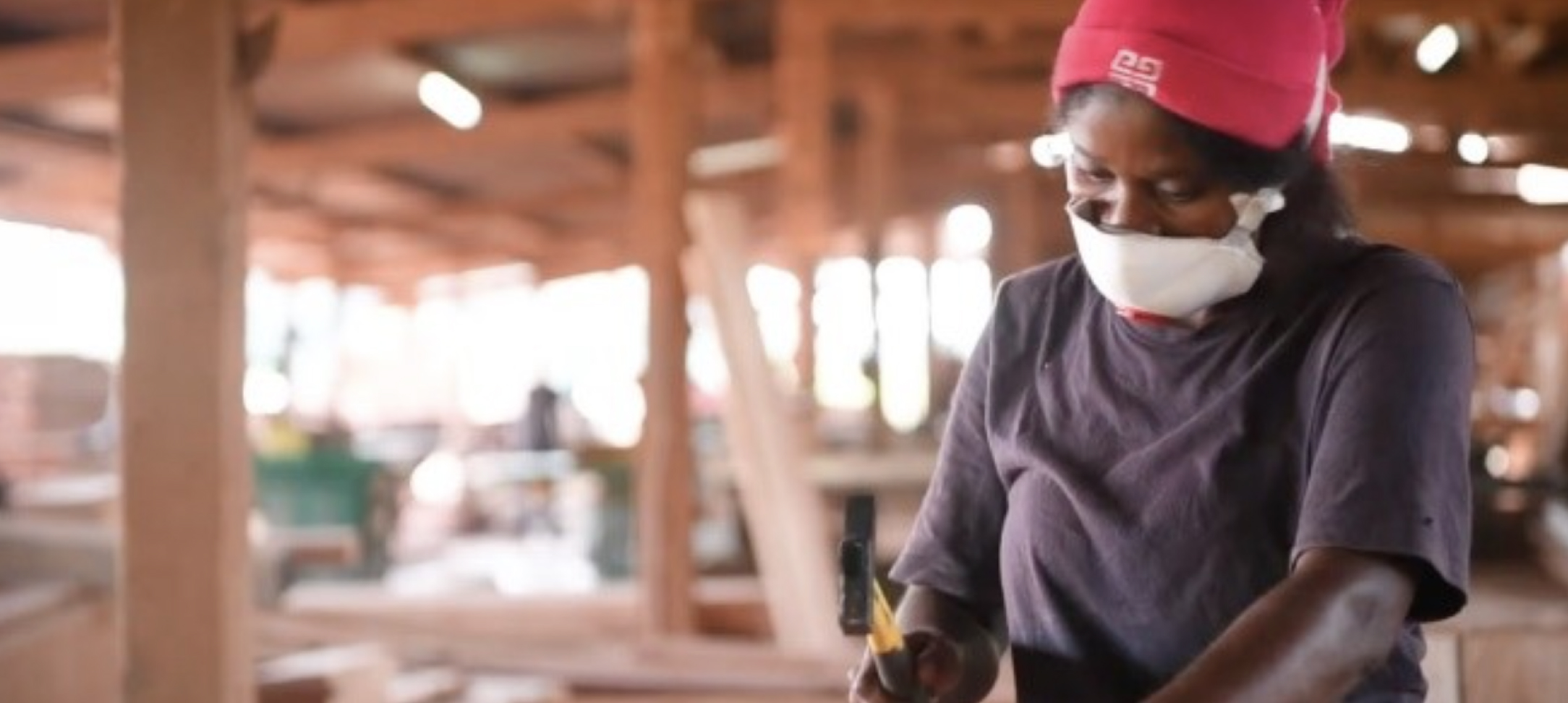 Woman hammering a nail into a wood plank